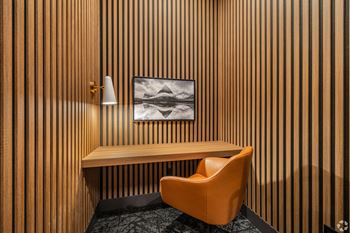 A chair sits in front of a wooden panelled wall with a picture hanging above it.